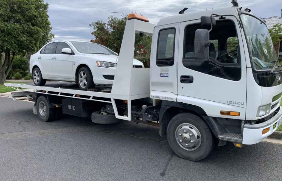 Professional flatbed tow truck operator transporting a sedan safely in Leucadia, CA