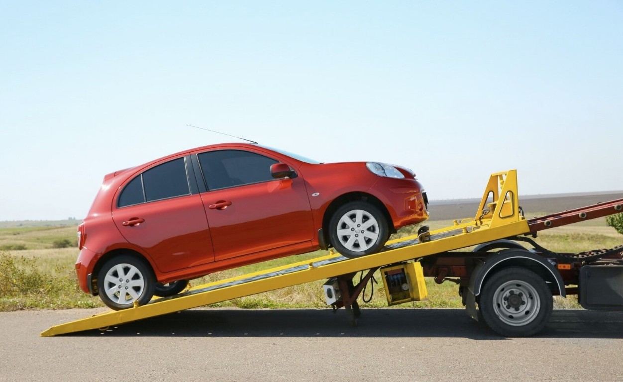 Flatbed tow truck using a ramp to recover a vehicle stuck off the road